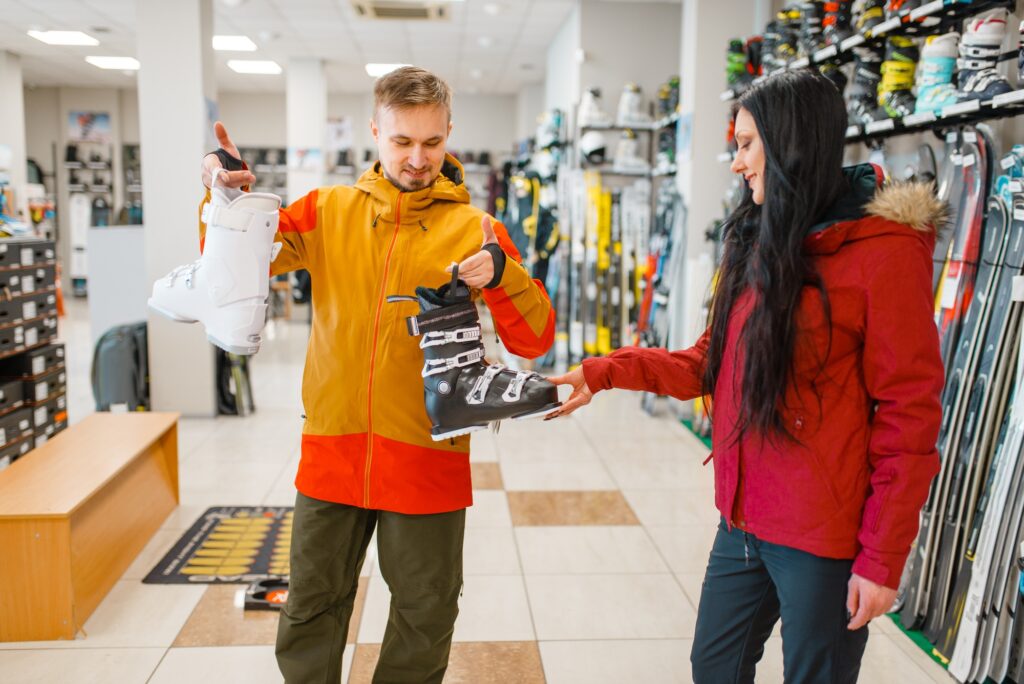 Couple choosing ski boots, shopping, sports shop